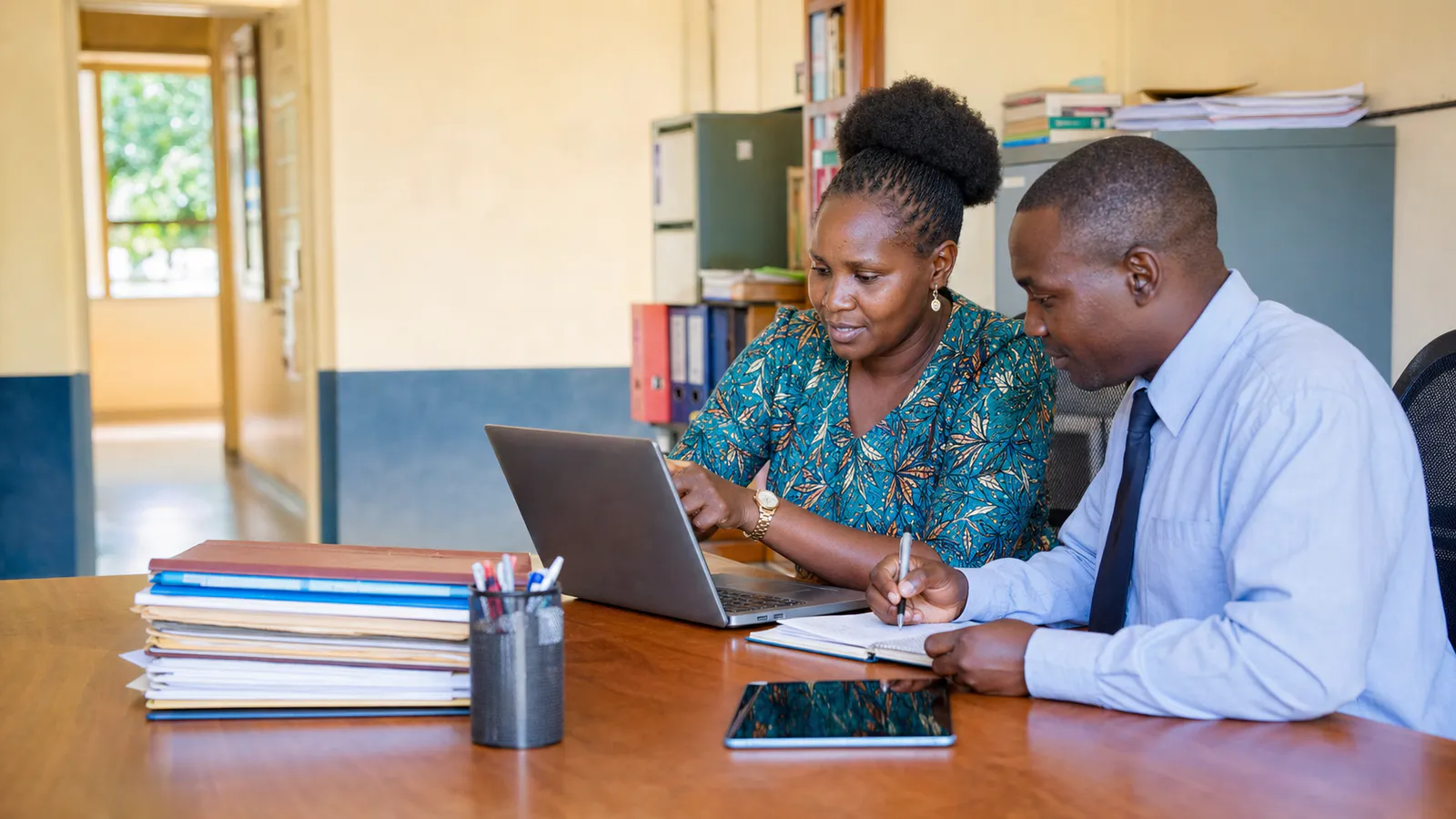 Ugandan school administrators setting up school records together
